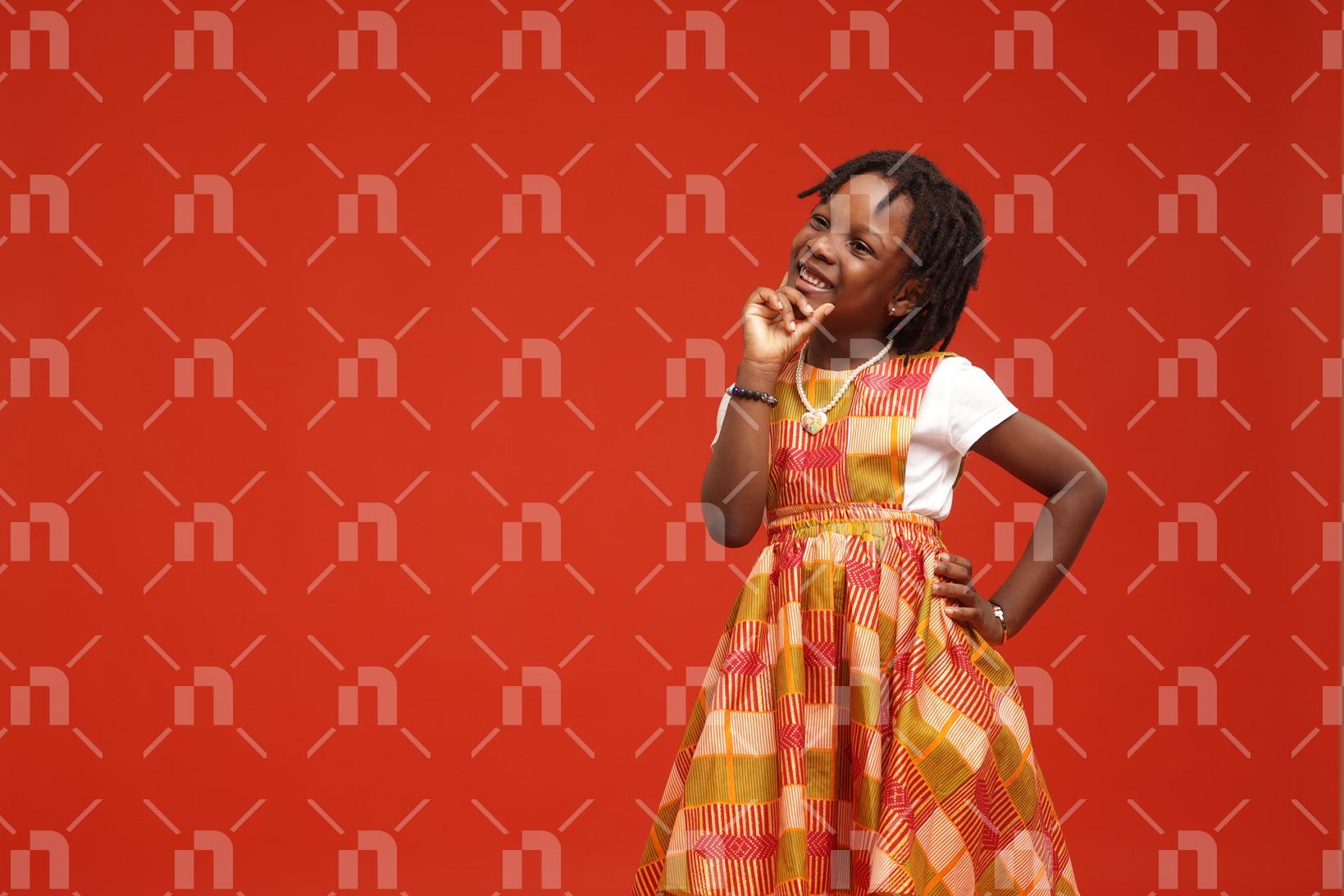 jeune-fille-africaine-vetue-dune-robe-coloree-la-main-sur-le-menton-avec-le-sourire-en-photo-studio