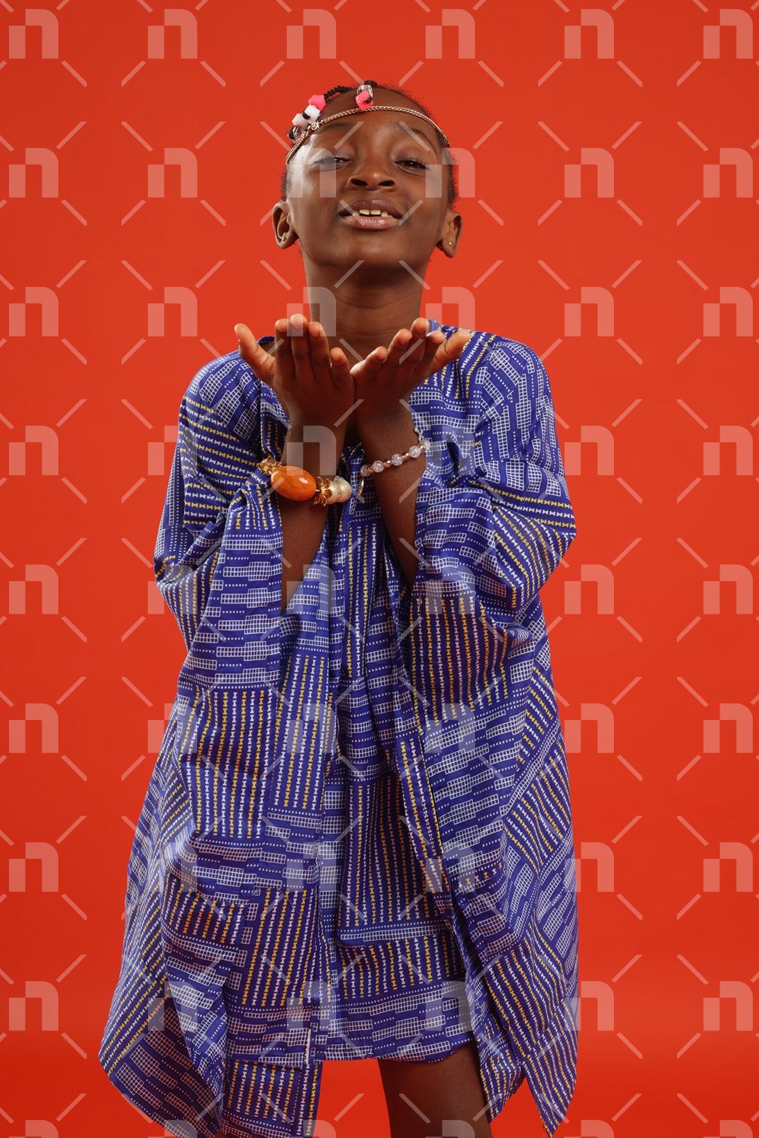fillette-africaine-moderne-vetue-dune-robe-de-couleur-bleu-ayant-les-deux-mains-jointes-avec-les-paumes-en-direction-du-ciel-accompagnees-dun-grand-sourire-pour-une-photo-studio
