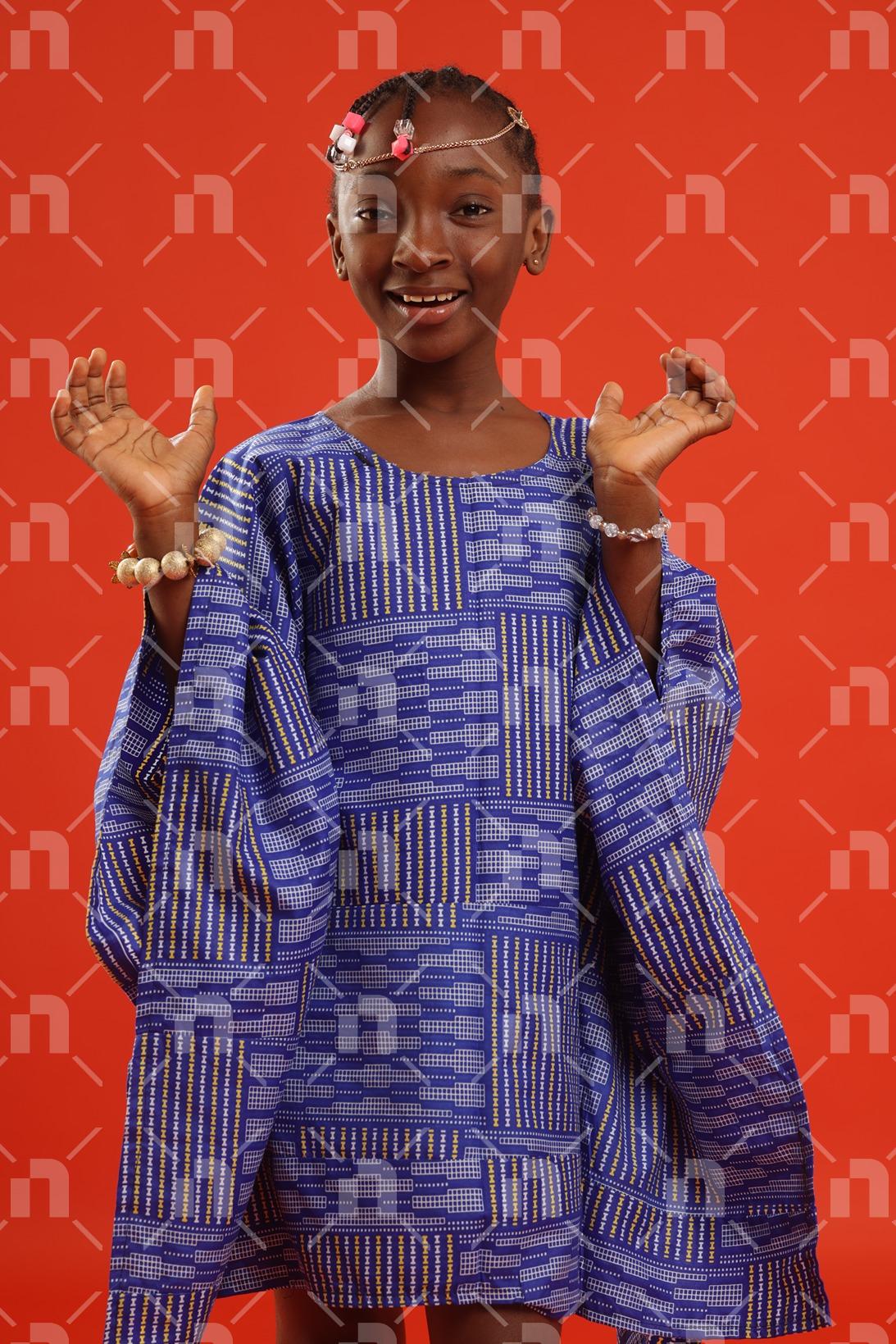 fillette-africaine-moderne-vetue-dune-robe-de-couleur-bleu-servant-un-sourire-de-bienvenue-pour-une-photo-studio