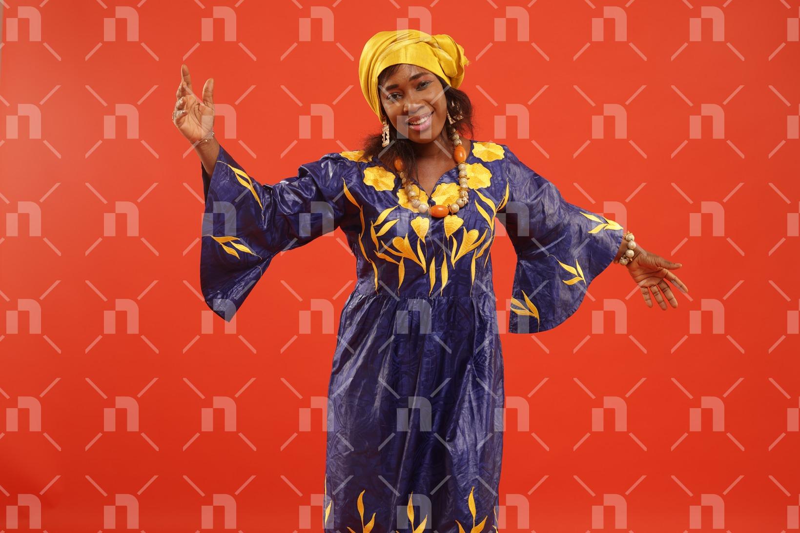 femme-vetue-en-boubou-africain-fait-a-base-de-bazin-de-couleur-violette-dansant-avec-un-beau-sourire-pour-une-photo-studio