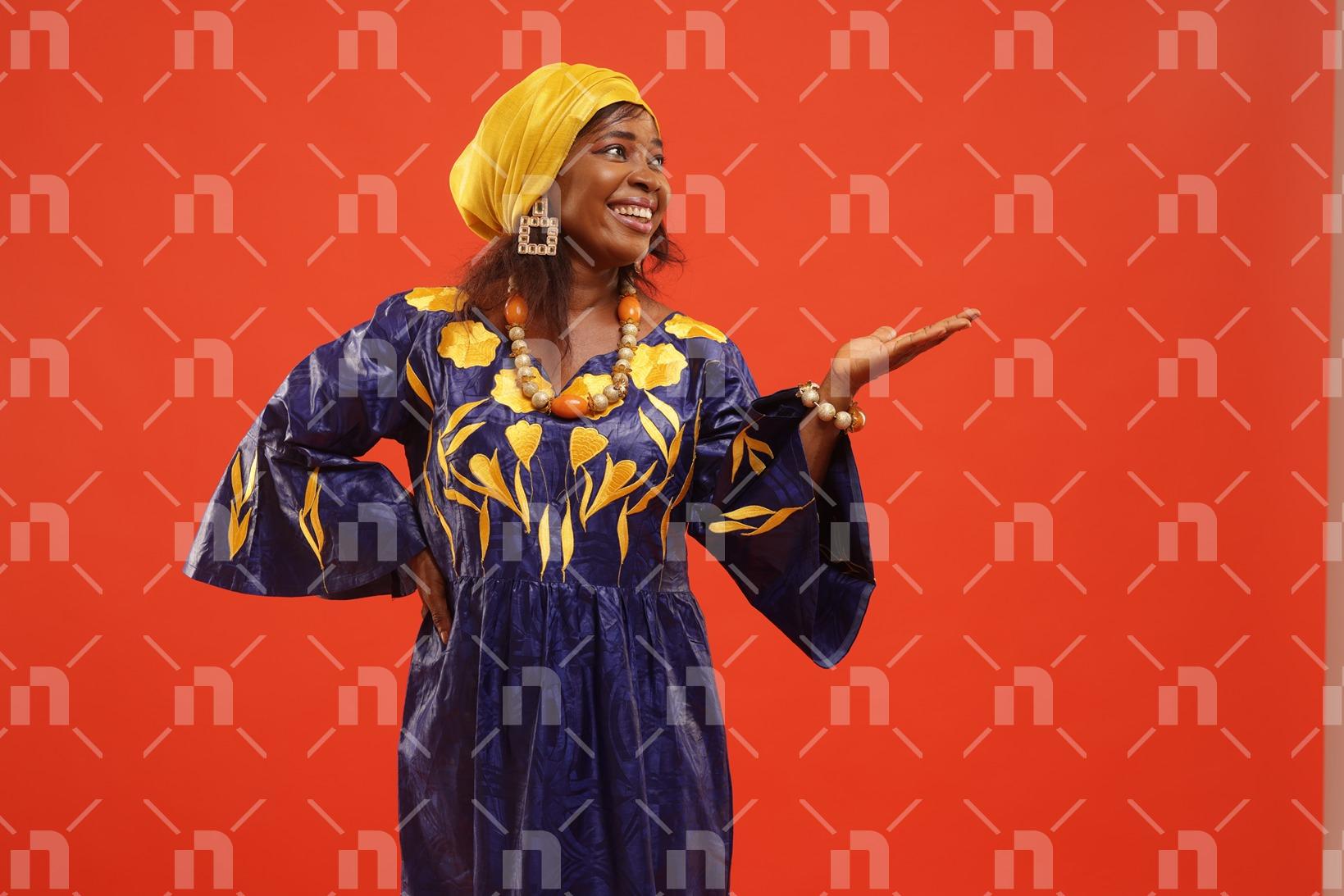 jeune-dame-africaine-en-robe-faite-avec-du-bazin-posant-pour-une-photo-studio-en-ayant-le-sourire-aux-levres-et-la-main-droite-sur-les-hanches