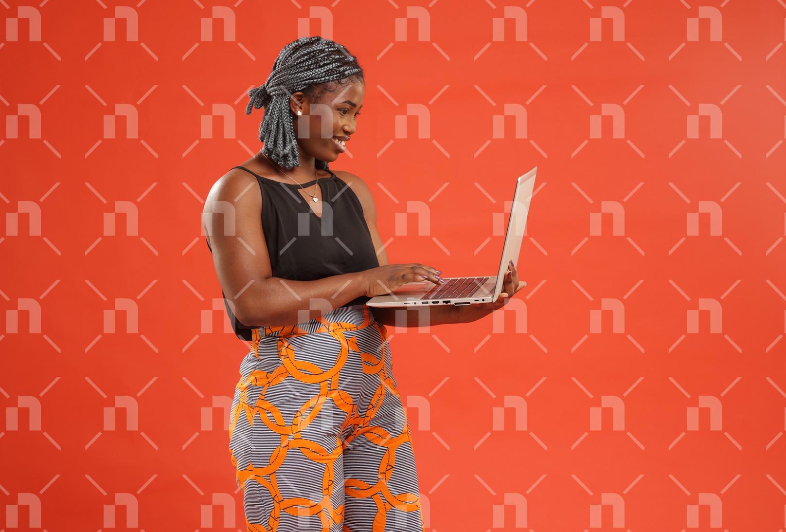 jeune-femme-africaine-tenant-et-manipulant-un-ordinateur-portable-pose-dans-sa-main-avec-le-sourire-pour-une-photo-studio