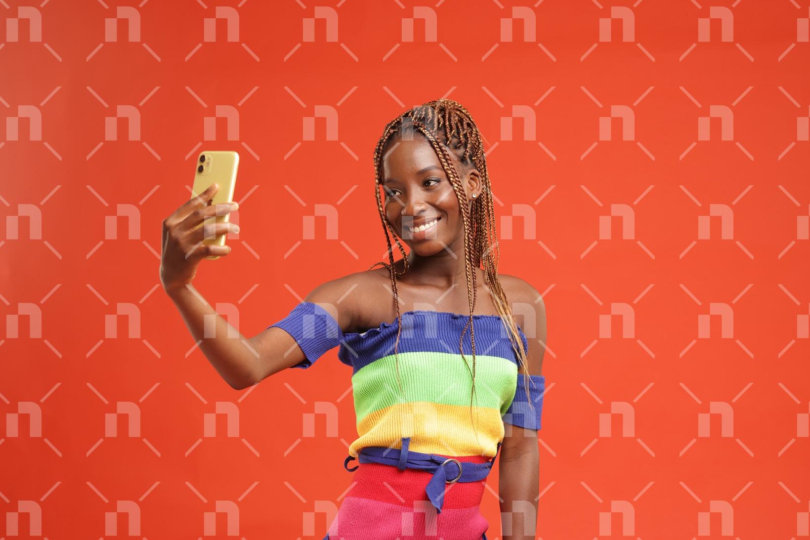fille-africaine-moderne-vetue-dune-robe-arc-en-ciel-heureuse-de-se-faire-un-selfie-avec-un-sourire-pour-une-photo-studio