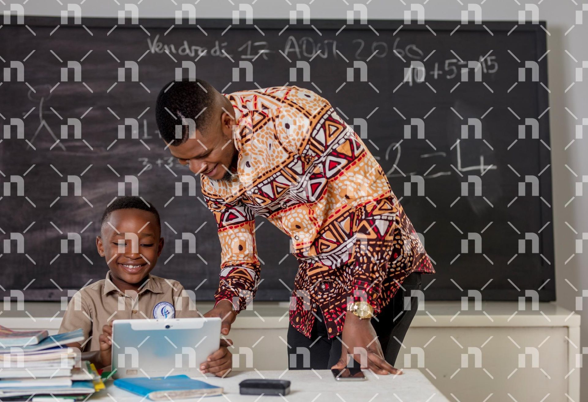 un-enfant-en-tenue-scolaire-kaki-tenant-une-tablette-avec-son-maitre-dans-une-salle-de-classe