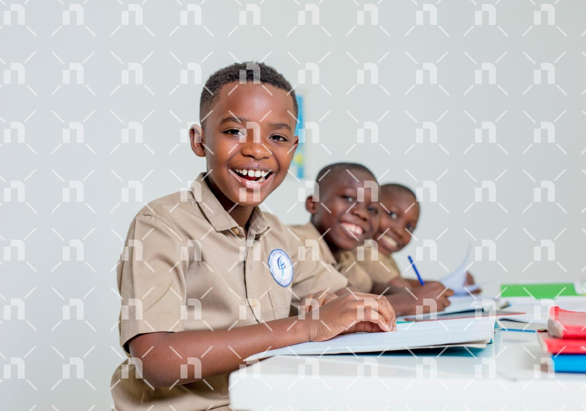 groupe-deleves-du-primaire-en-tenue-scolaire-kaki-assis-dans-une-salle-de-classe-et-affichant-tous-un-sourire