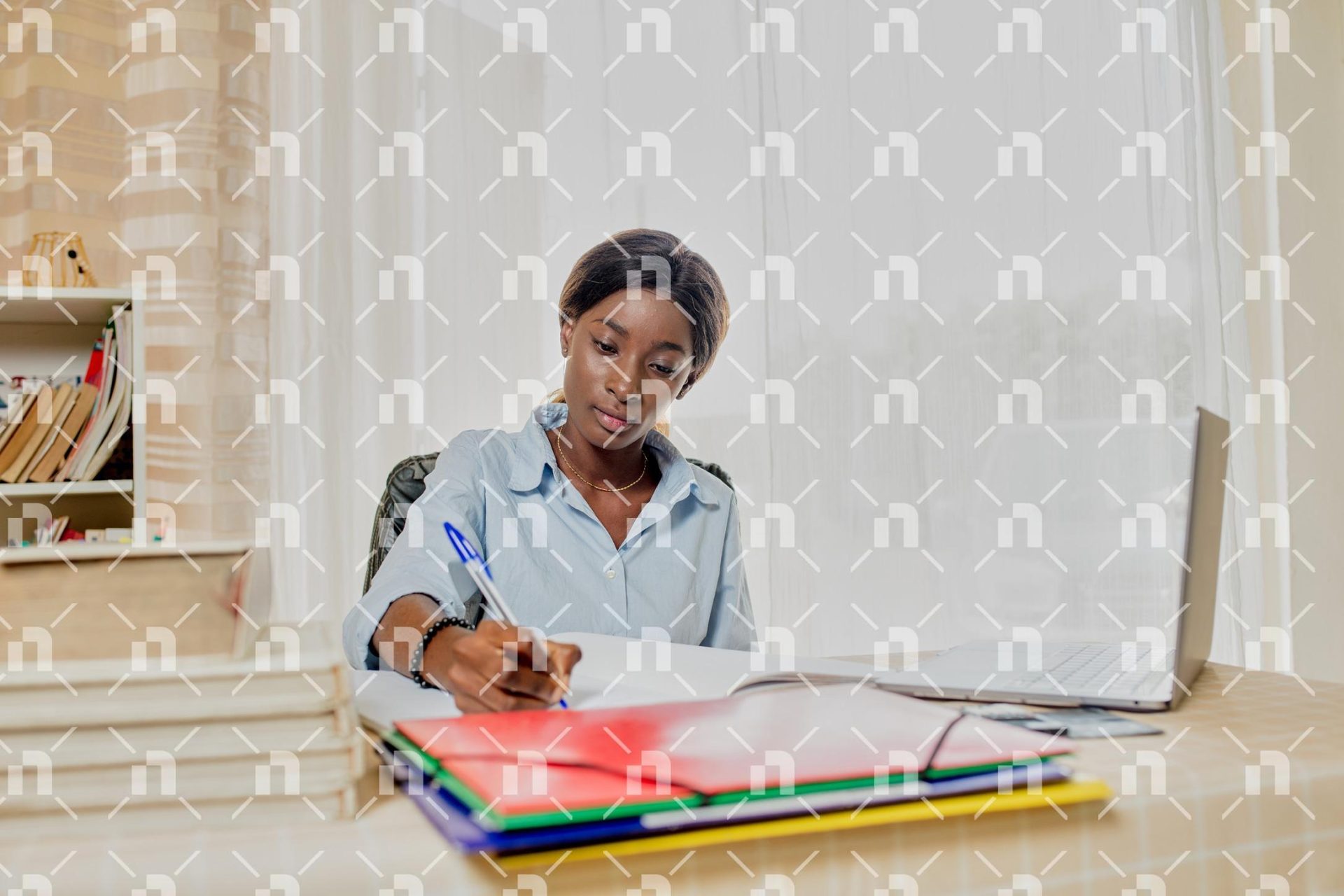 jeune-femme-studieuse-dorigine-africaine-travaillant-a-son-bureau-sur-lequel-est-pose-son-ordinateur-portable-et-des-porte-documents