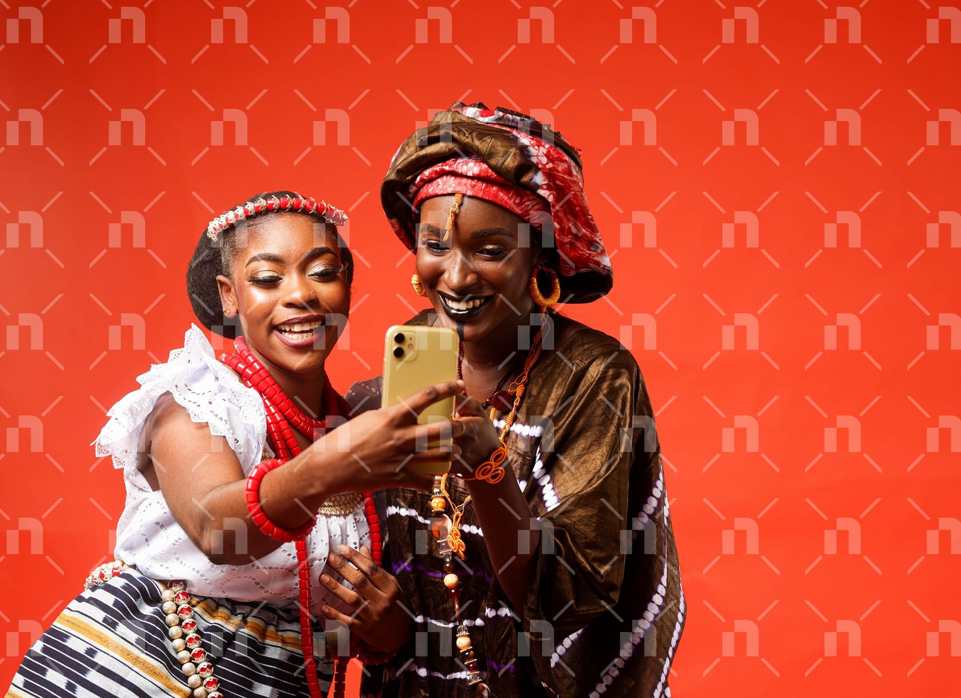 deux-femmes-heureuses-en-tenues-traditionnelle-regardant-dans-une-telephone
