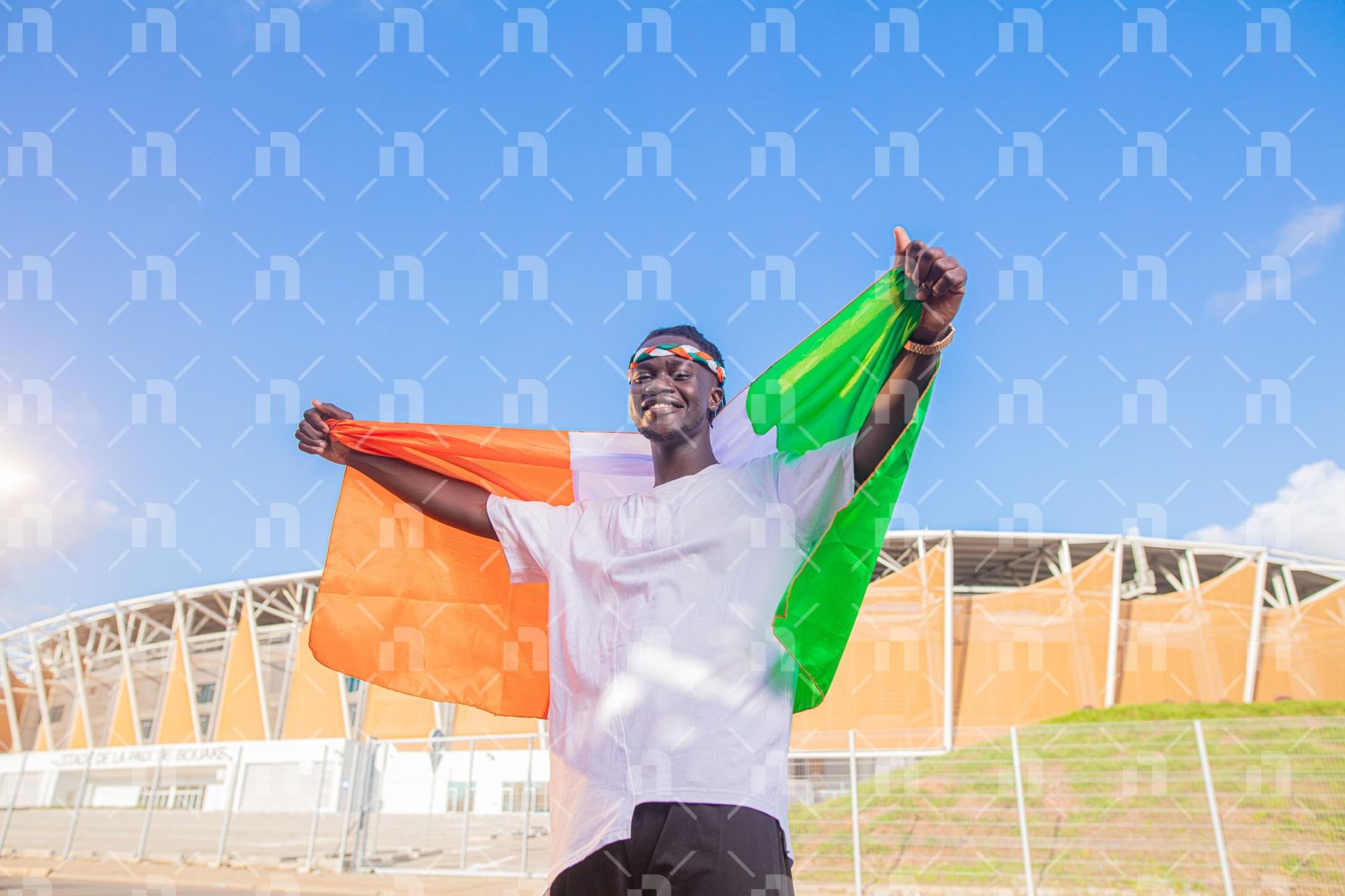 supporteur-ivoirien-tenant-le-drapeau-avec-fierte-derriere-le-stade