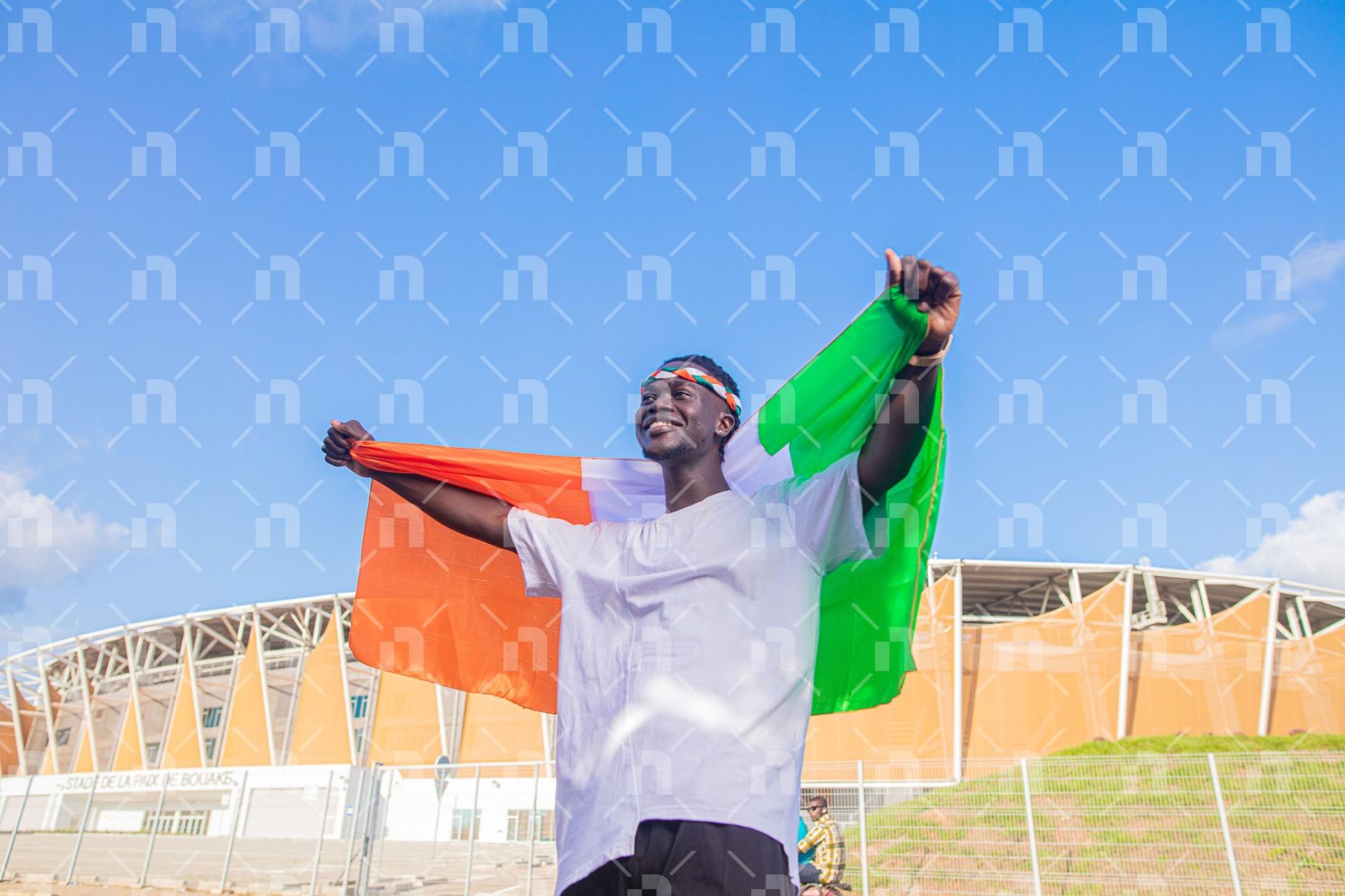 supporteur-ivoirien-tenant-le-drapeau-avec-fierte-derriere-le-stade-avec-le-regard-hors-champ